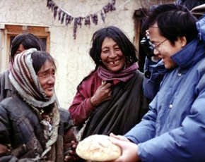 In 1996, Tzu Chi provides relief aid in Yushu, Qinghai. Wang Tuan-cheng (left), vice president of Tzu Chi Foundation, brings the traditional Tibetan food to a woman. (Photo by Lin Ying-ching; location: Qinghai, China)